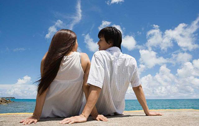 幸福的情侣坐在海边谈情说爱
