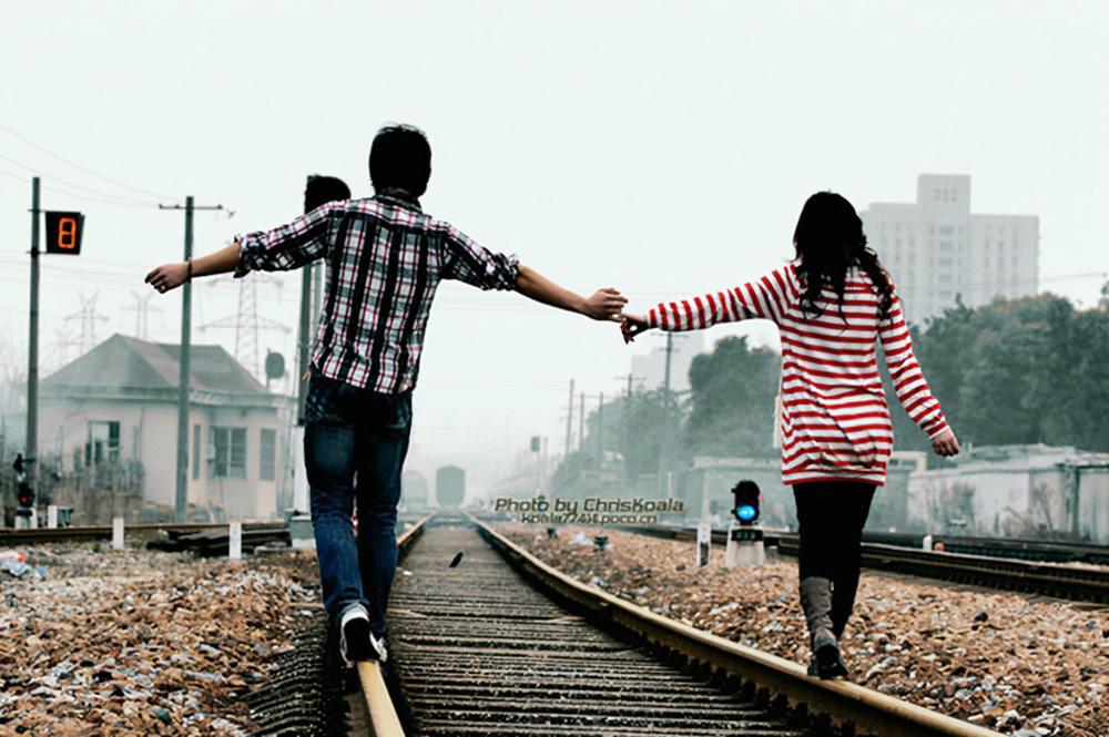年轻的小情侣在铁轨上散步